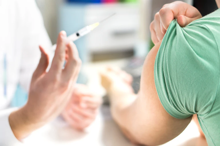 Doctor's hand with syringe and man holding sleeve of shirt up