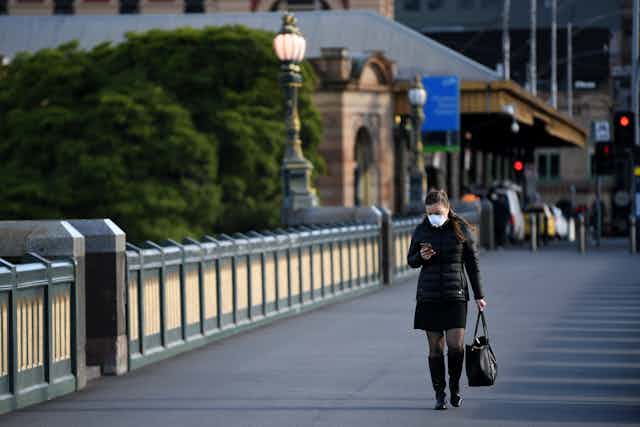 A person walking in Melbourne while wearing a mask