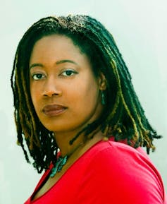Photograph of author NK Jemisin, a Black woman wearing a red top.