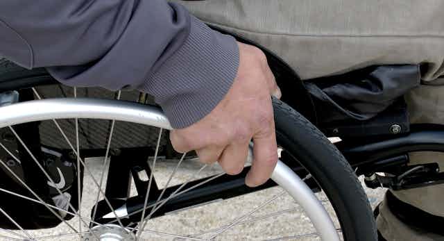 Man's hand on wheel of wheelchair.