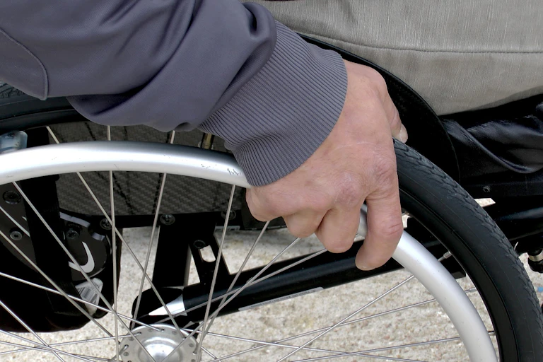 Man's hand on wheel of wheelchair.