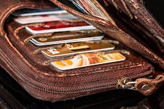 A weathered brown wallet stuffed with credit cards