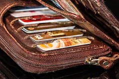 A weathered brown wallet stuffed with credit cards