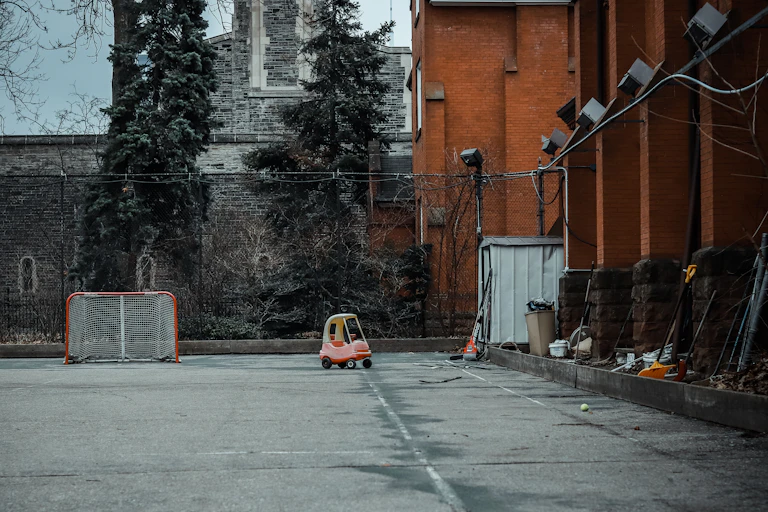An empty schoolyard, with a hockey goal and toddler car in the background.