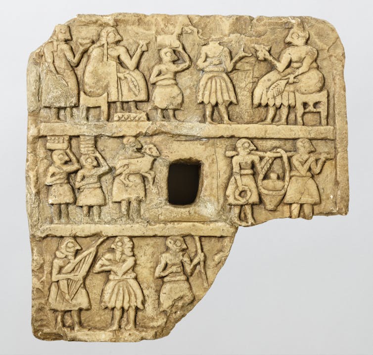 Stone plaque showing people gathered drinking out of cups