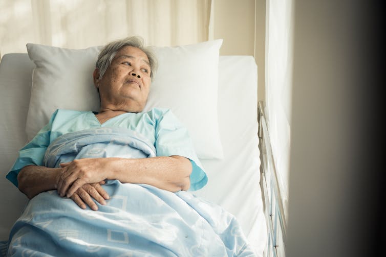 Elderly woman lying in hospital bed.