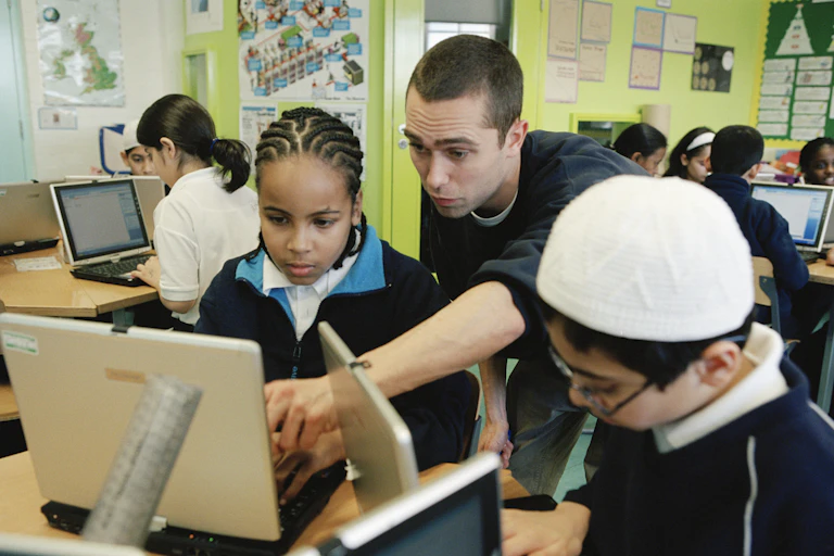 Teacher pointing at student's computer screen