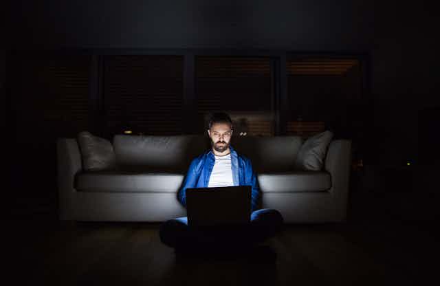 Man using laptop in the dark.