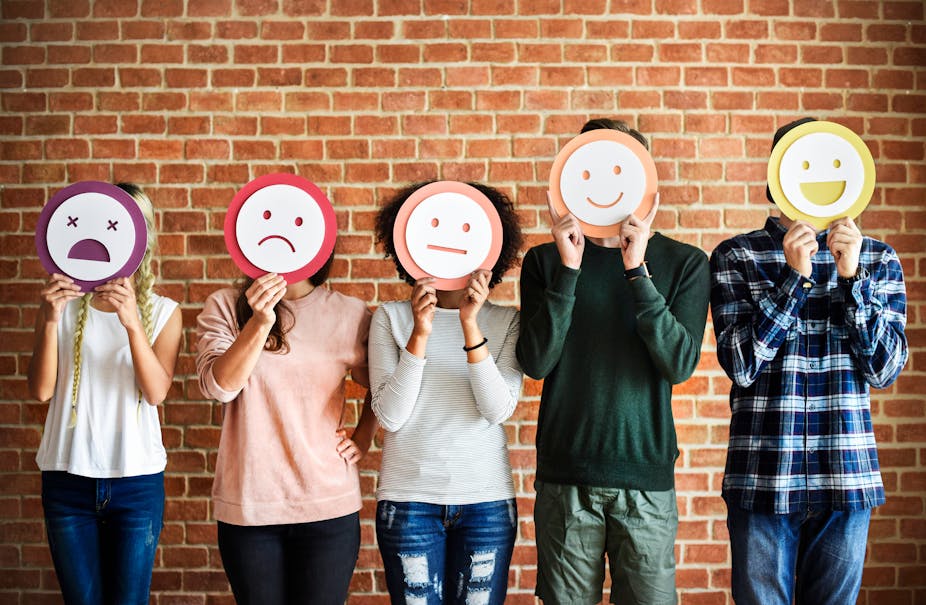 Five people hold up different emotion masks over their faces.