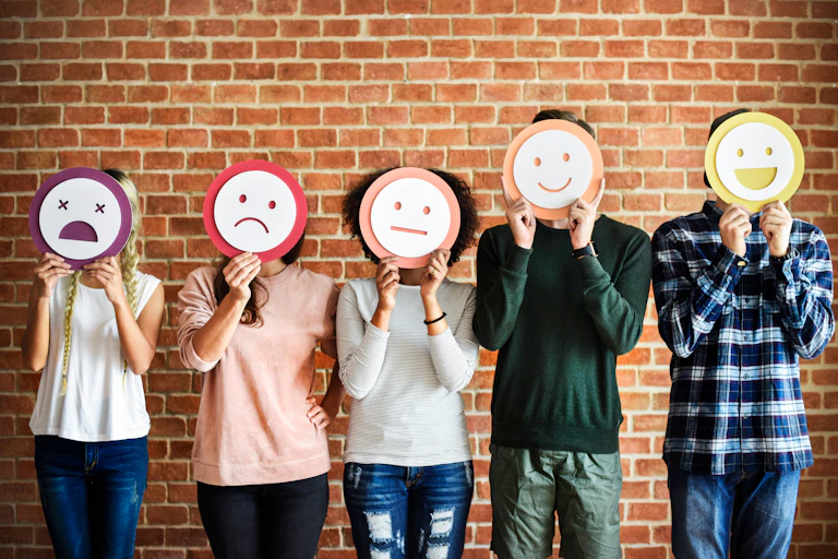 Five people hold up different emotion masks over their faces.