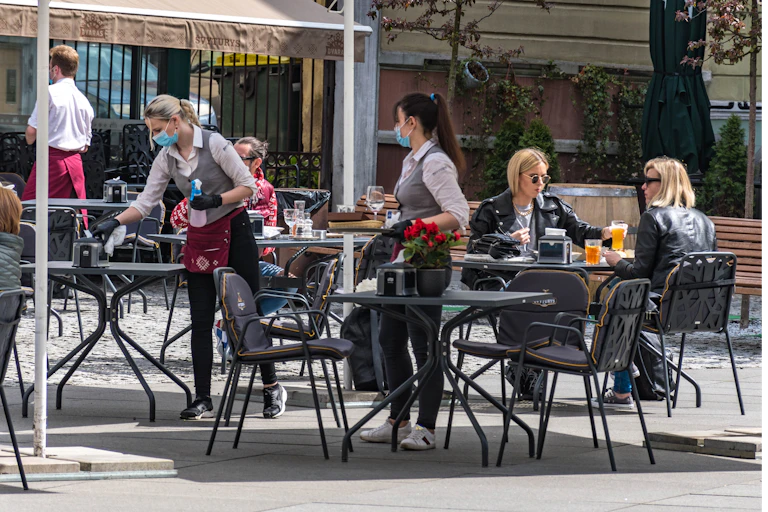 Waitresses with masks and gloves disinfect tables
