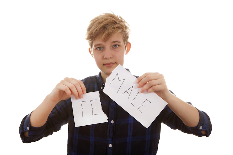 Transgender person tearing up piece of paper with FEMALE written on it