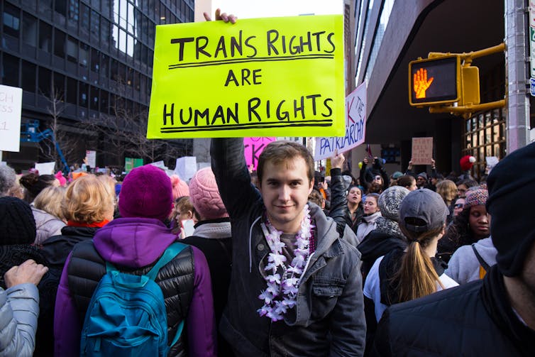 A person holds a sign that reads: 'Trans Rights Are Human Rights' at a march.