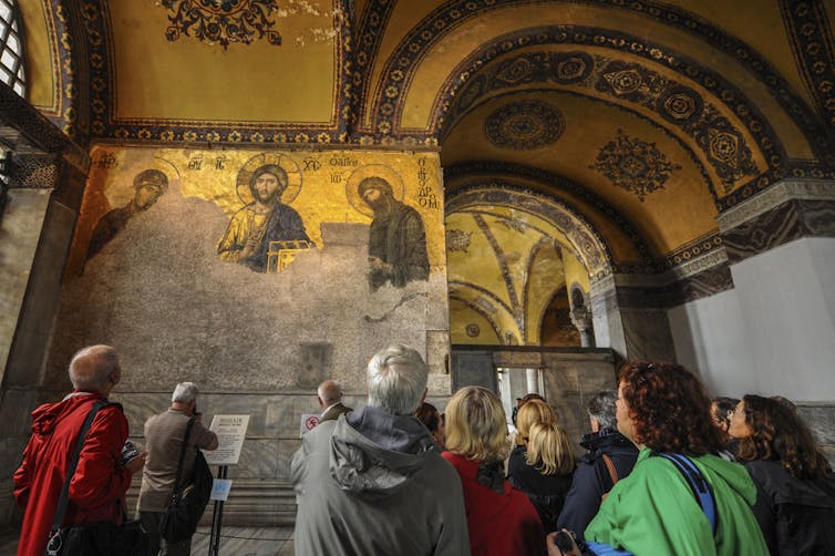 Visitors inside Hagia Sophia in front of Jesus Christ's mosaic