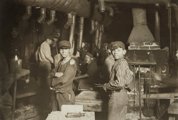 Two boys working in a glass factory in the early 1900s.
