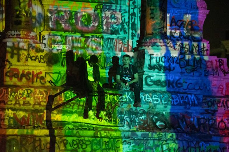 Protesters sit on the graffiti-covered monument to Confederate General Robert E. Lee