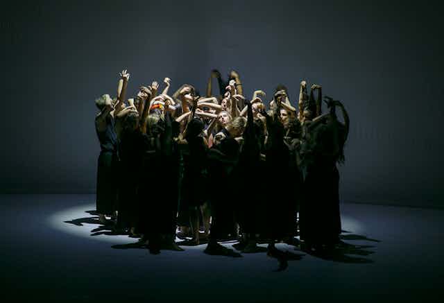 A group of dancers reach upwards.