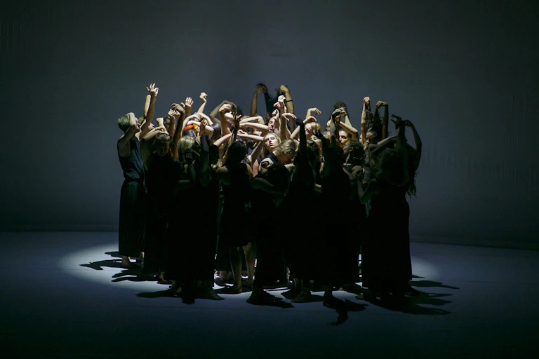 A group of dancers reach upwards.