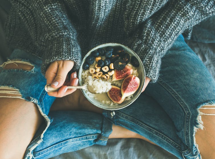 hygiene Woman holds healthy breakfast bowl with blueberries, guava and cereal.