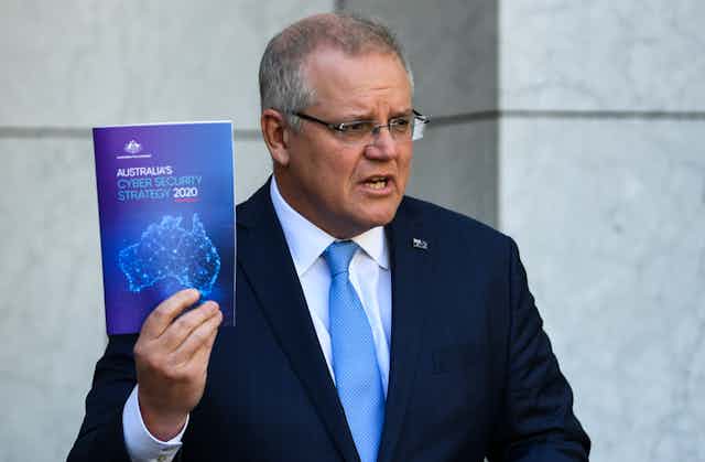 Australian Prime Minister Scott Morrison holds up a copy of Australia's Cyber Security Strategy 2020