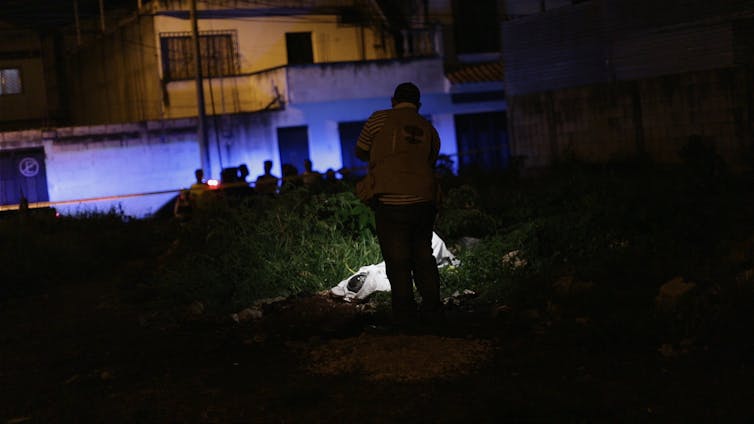 Man photographs dead body at nighttime.