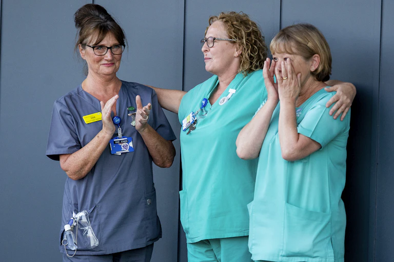 Three women healthcare professionals outside an NHS hospital