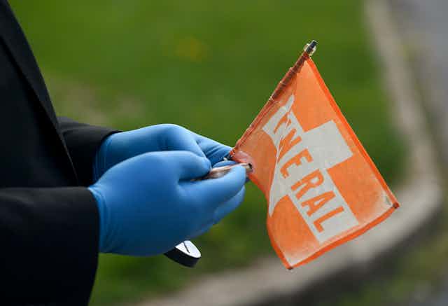 Gloved hands holding small funeral flag for car