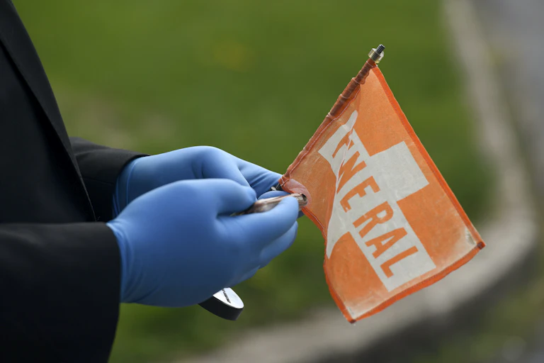 Gloved hands holding small funeral flag for car