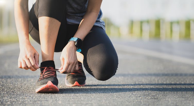 A woman lacing her shoes ahead of going for a run.