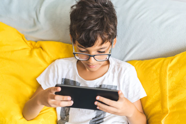 Boy uses a digital tablet on a yellow sofa.