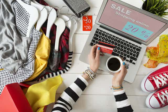 A person holding a credit card looks at an online sale site.