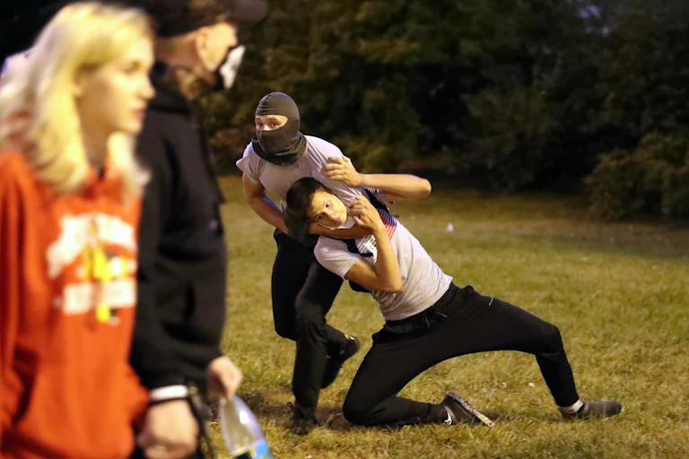 A man in a balaclava holds another in a headlock during protests in Belarus.
