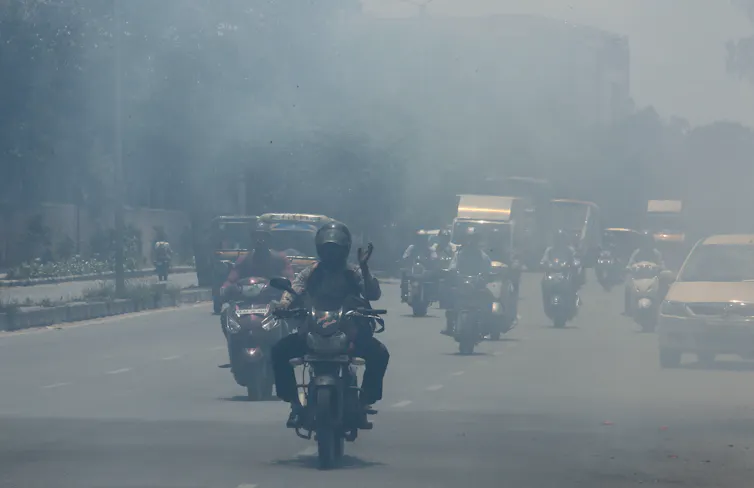 A road in Bangalore crowded with motorcycles and cars under a thick haze.