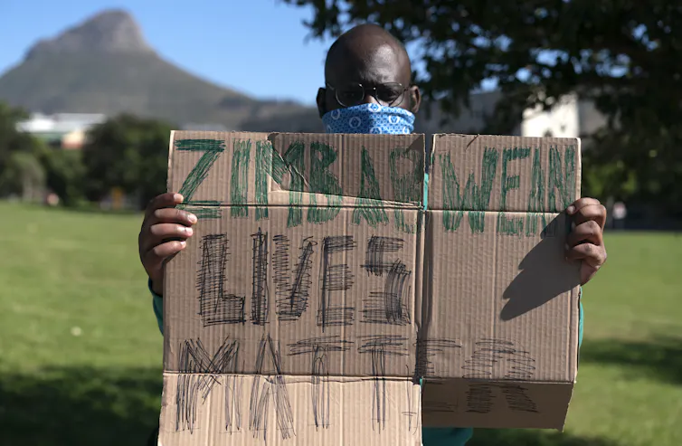 Protestor holds up sign: Zimbabwean Lives Matter