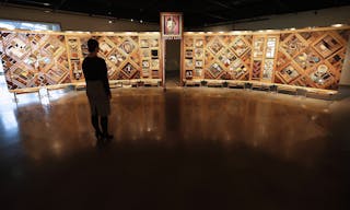 Una donna si trova di fronte alla mostra Witness Blanket al Museo Canadese per i Diritti Umani. La mostra presenta oggetti dell'era delle scuole residenziali tra cui distintivi e trofei, scarpe e una porta di una delle scuole.