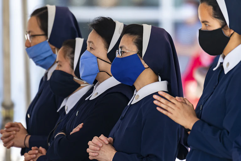 Four nuns wearing masks during a church service