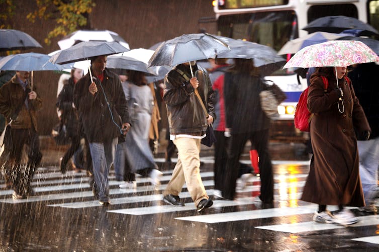 People cross a street holding umbrellas and in long coats during a winter storm in Philadelphia.