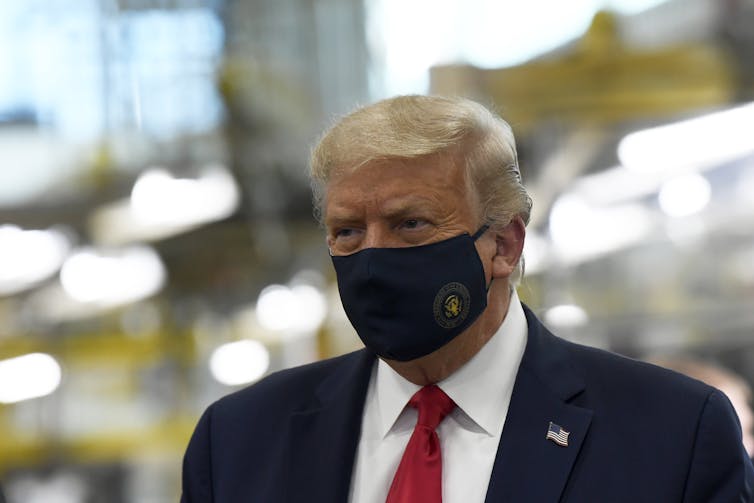 Donald Trump with a mask on at a factory
