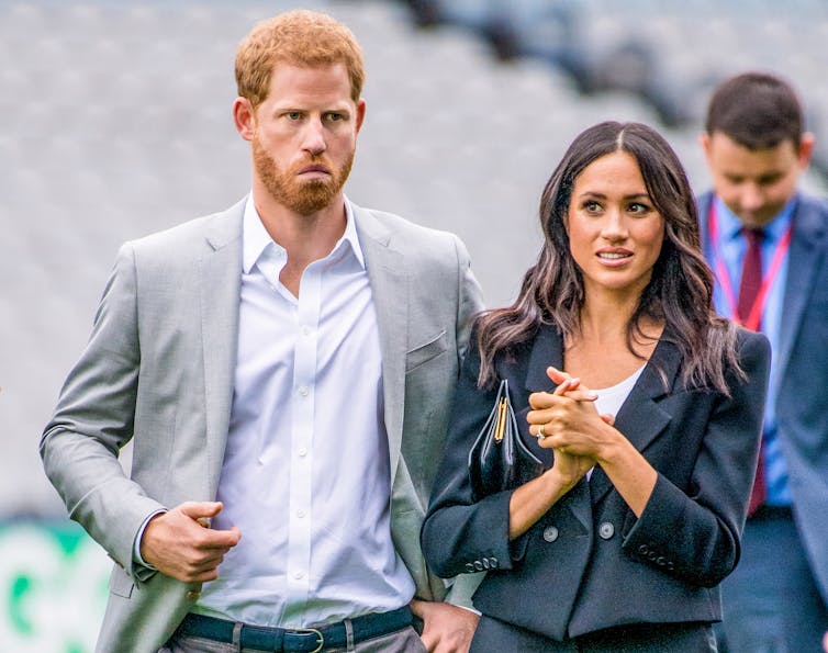 Harry and Meghan looking uncertain at public event.