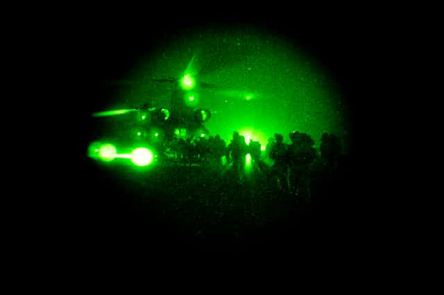 Special operations taskgroup soldiers file into a chinook under cover of darkness