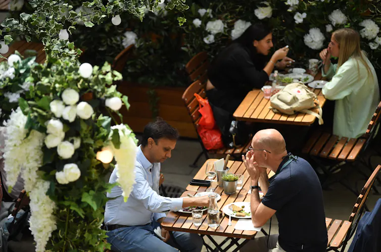 People eating outside at a restaurant at socially distanced tables.