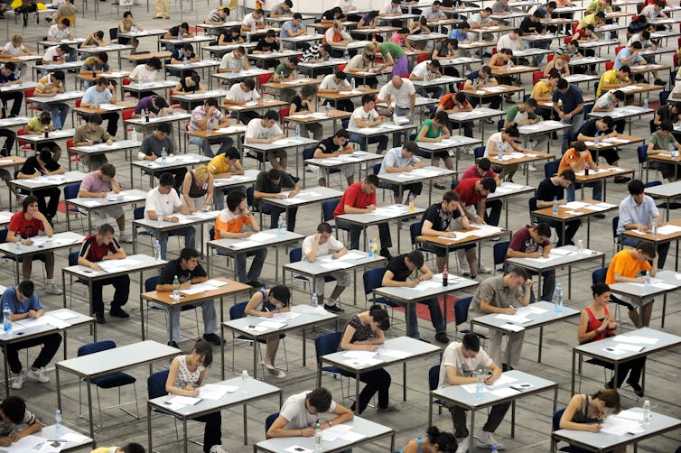 Exam hall full of pupils deep in concentration.