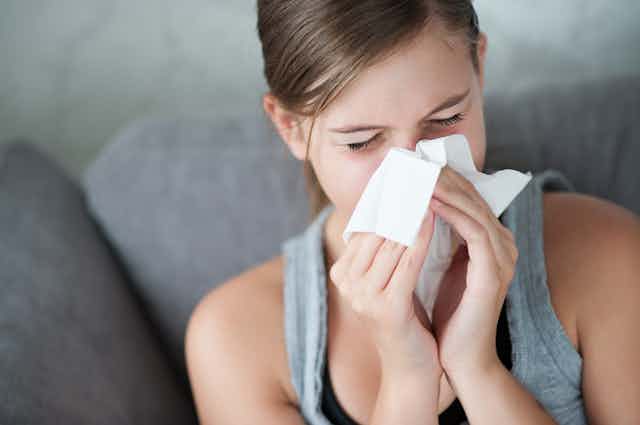 Woman with a common cold, blowing her nose
