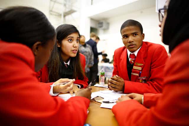 Four high school students sit around a table in discussion