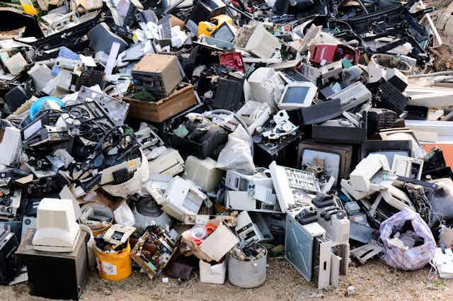 A mountain of electronic waste, including computer monitors and printers.