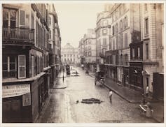 Zdjęcie zmodernizowanej paryskiej ulicy, z szeroką, brukowaną drogą, nowymi budynkami i oświetleniem gazowym.