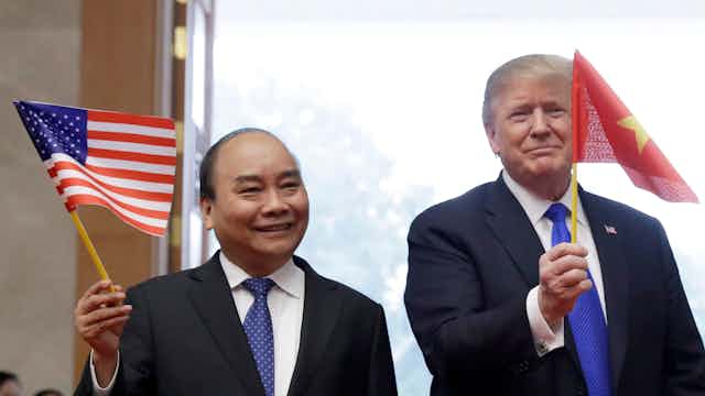 U.S. President Donald Trump waves a Vietnam flag as Vietnamese Prime Minister Nguyen Xuan Phuc waves an American flag.
