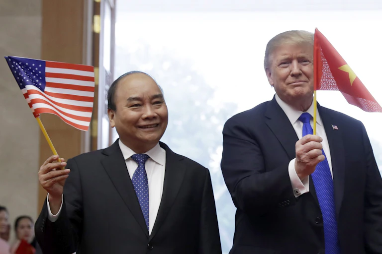 U.S. President Donald Trump waves a Vietnam flag as Vietnamese Prime Minister Nguyen Xuan Phuc waves an American flag.