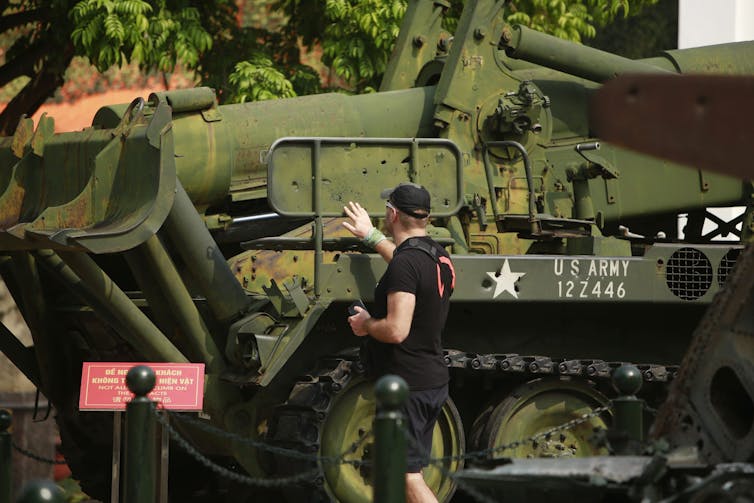 A person touches bullet holes on a U.S. artillery launcher