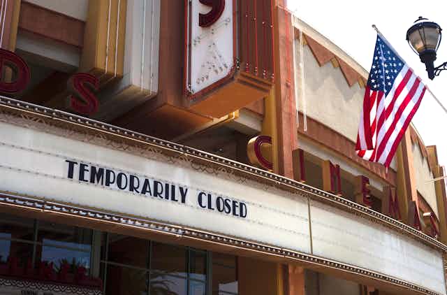 The exterior of a movie theater has the words 'temporarily closed' posted.